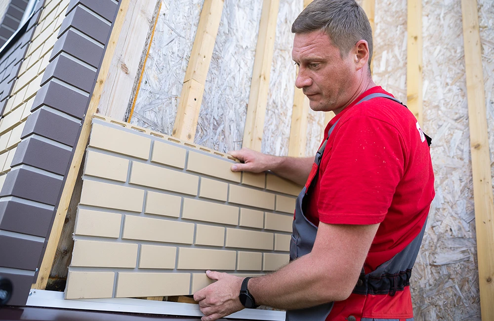 Вставьте левый край панели в паз наружного угла, закрепленного на каркасе. Нижний замок панели в зависимости от коллекции установите на стартовую планку или вставьте в J-профиль. Между левым краем панели и доборным элементом оставьте температурный зазор 10–15 мм.