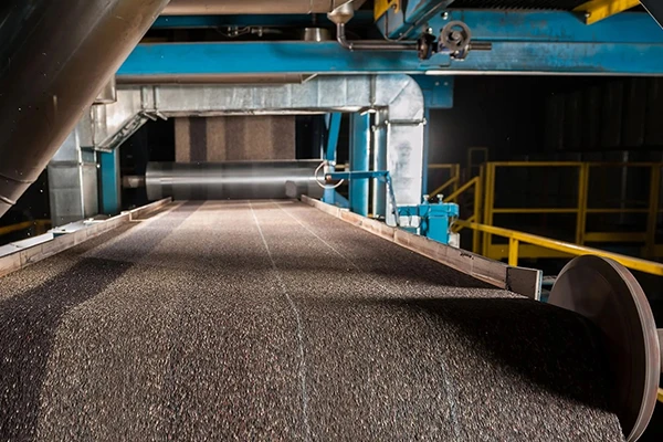 После нанесения гранул полотно проходит через прикаточный вал — это нужно, чтобы они плотно сцепились и спрессовались, превратившись в единое покрытие.