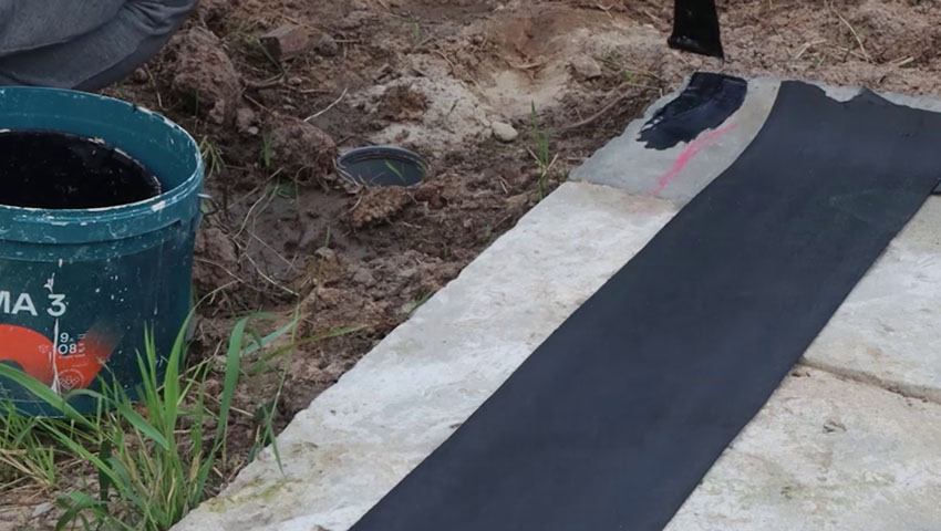 Максим первым делом промазал края плиты мастикой, она служит дополнительной защитой от влаги, а еще фиксирует гидроизоляцию — это рулон справа