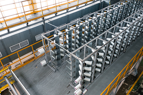 Нити наматывают на большие бобины. Это похоже на ткацкий станок, но тут ничего не ткут