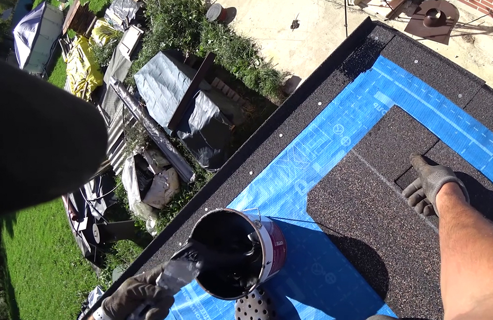 Начало монтажа: торцевую планку промазывают мастикой, это же можно сделать на всякий случай и с карнизной планкой. Обратите внимание, что у крайнего гонта чуть срезан край — это делают вручную по всему краю, так же надо и с другого края. Стекающая вода благодаря этим срезам направится вдоль планки вниз, а не будет подтачивать крайние гонты, стремясь их оторвать