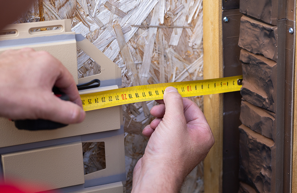 Чтобы отрезать последнюю панель, рулеткой измерьте расстояние от уже установленной панели до торца паза доборного элемента, вычтите из полученной величины 10–15 мм на температурный зазор, разметьте и обрежьте панель. Установите ее на фасад.