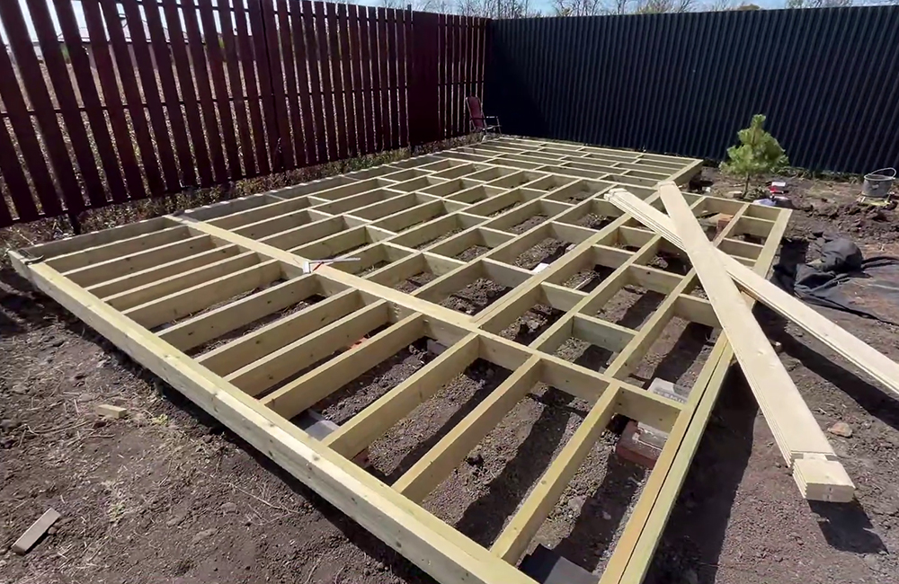 Готовая обвязка — сдвоенные доски 50 × 150 мм по периметру. Плюс готовое нижнее перекрытие — одинарные доски внутри, которые образуют решетку под пол. Всё собирают на гвозди 120 мм, которые идут в комплекте.